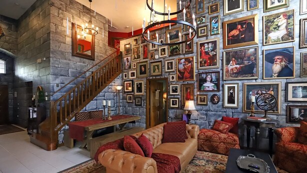 Ein geräumiges Wohnzimmer mit Steinwand, einer Holztreppe und einer großen Sammlung gerahmter Bilder an der Wand.