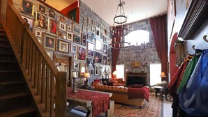 Ein geräumiges Wohnzimmer mit Kamin, einer Treppe und einer Wand mit gerahmten Bildern.