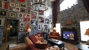 Ein gemütliches Wohnzimmer mit Steinwand, Kamin und Fernseher, der verschiedene Sender anzeigt.
