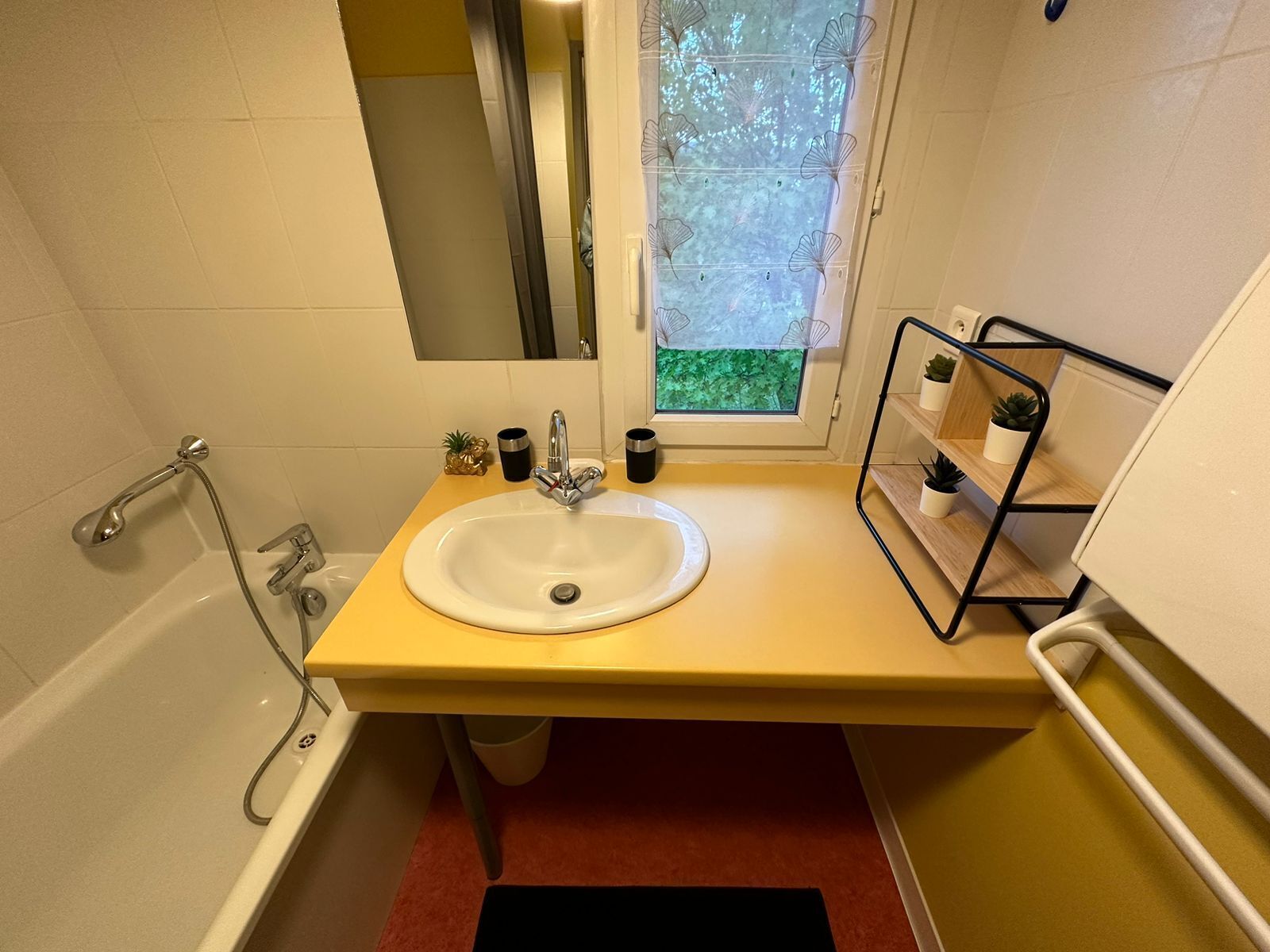 A bathroom with a bathtub, a sink, and a window with a view of greenery.