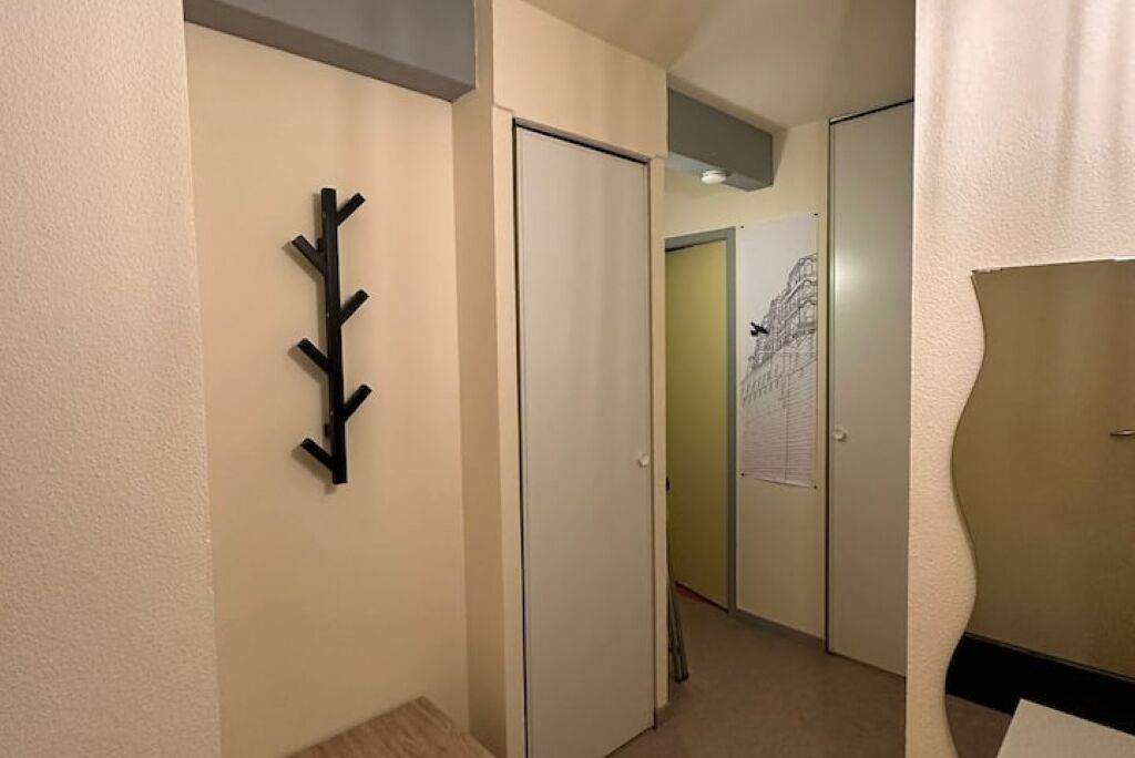 Un pasillo con un perchero, una puerta cerrada y una puerta con un papel pegado.
