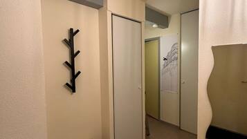 Un pasillo con un perchero, una puerta cerrada y una puerta con un papel pegado.
