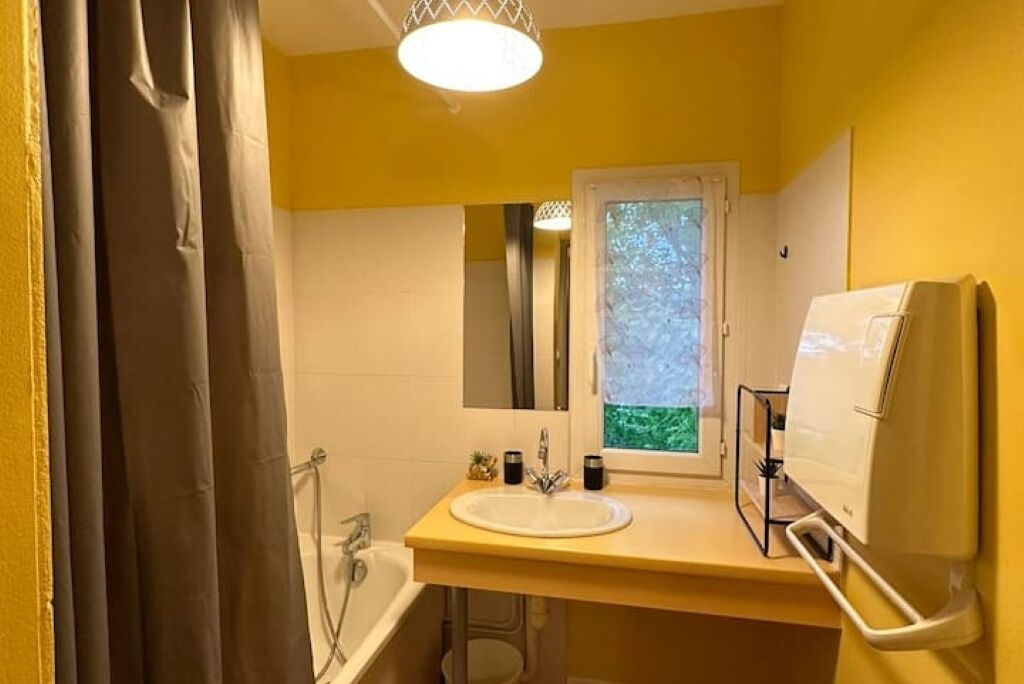 A bathroom with a white sink, a mirror, and a window.