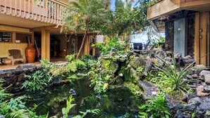 Une cour avec un bassin, une végétation luxuriante et un bâtiment doté d’un balcon.