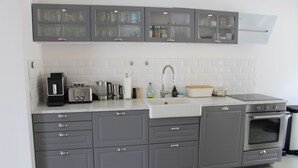 A kitchen with grey cabinets, a white sink, and a built-in oven.