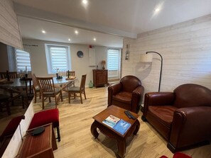 A living room with a wooden floor, a dining area with a table and chairs, and a seating area with a sofa and armchairs.