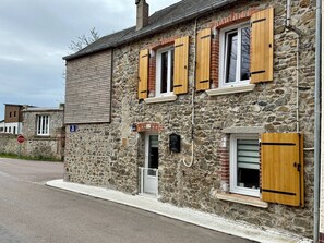 A stone building with wooden shutters, a stop sign, and a small window.