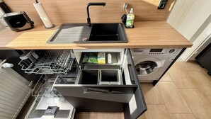 Una cocina compacta con lavavajillas integrado, un lavamanos y una lavadora.