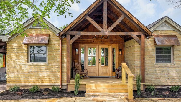 A stone house with a wooden porch and a front door. - Charming 3-bed 3-bath, country cottage, fully renovated, on the edge of town. (Sparta)