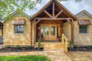 A stone house with a wooden porch and a front door.