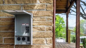 A utility box mounted on a stone wall, with a wooden deck and greenery in the background. - Charming 3-bed 3-bath, country cottage, fully renovated, on the edge of town. (Sparta)