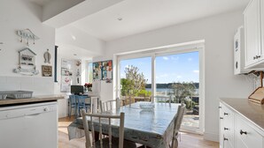 A modern kitchen with a dining area, large windows, and a view of the outdoors.