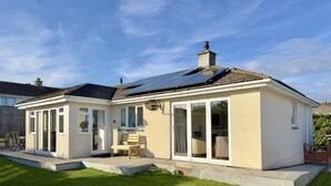Una casa con tetto solare, veranda con porte vetrate e prato ben curato.