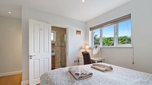 Una camera da letto con un letto, una finestra, una porta e un bagno visibile attraverso una porta aperta.