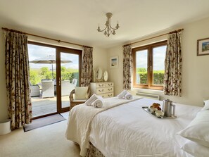 A bedroom with a bed, a dresser, a chair, and a view of the outdoors.