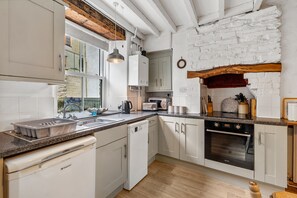 A kitchen with white cabinets, a built-in oven, a sink, and a window with a view of the outside.