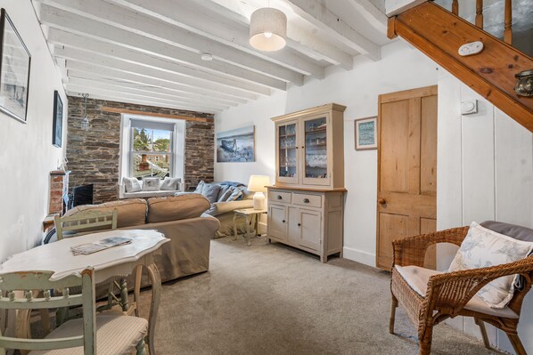 A cozy room with a stone wall, a wooden door, a wicker chair, a table, and a sofa.