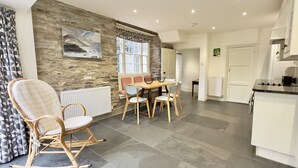 A modern kitchen with a dining area, stone wall, and a large window. - 36 High Street -  a two storey property that sleeps 6 guests  in 3 bedrooms (Padstow)