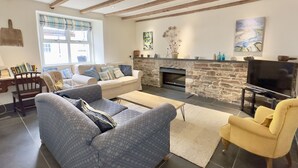 A cozy living room with a stone fireplace, a television, and comfortable seating. - 36 High Street -  a two storey property that sleeps 6 guests  in 3 bedrooms (Padstow)