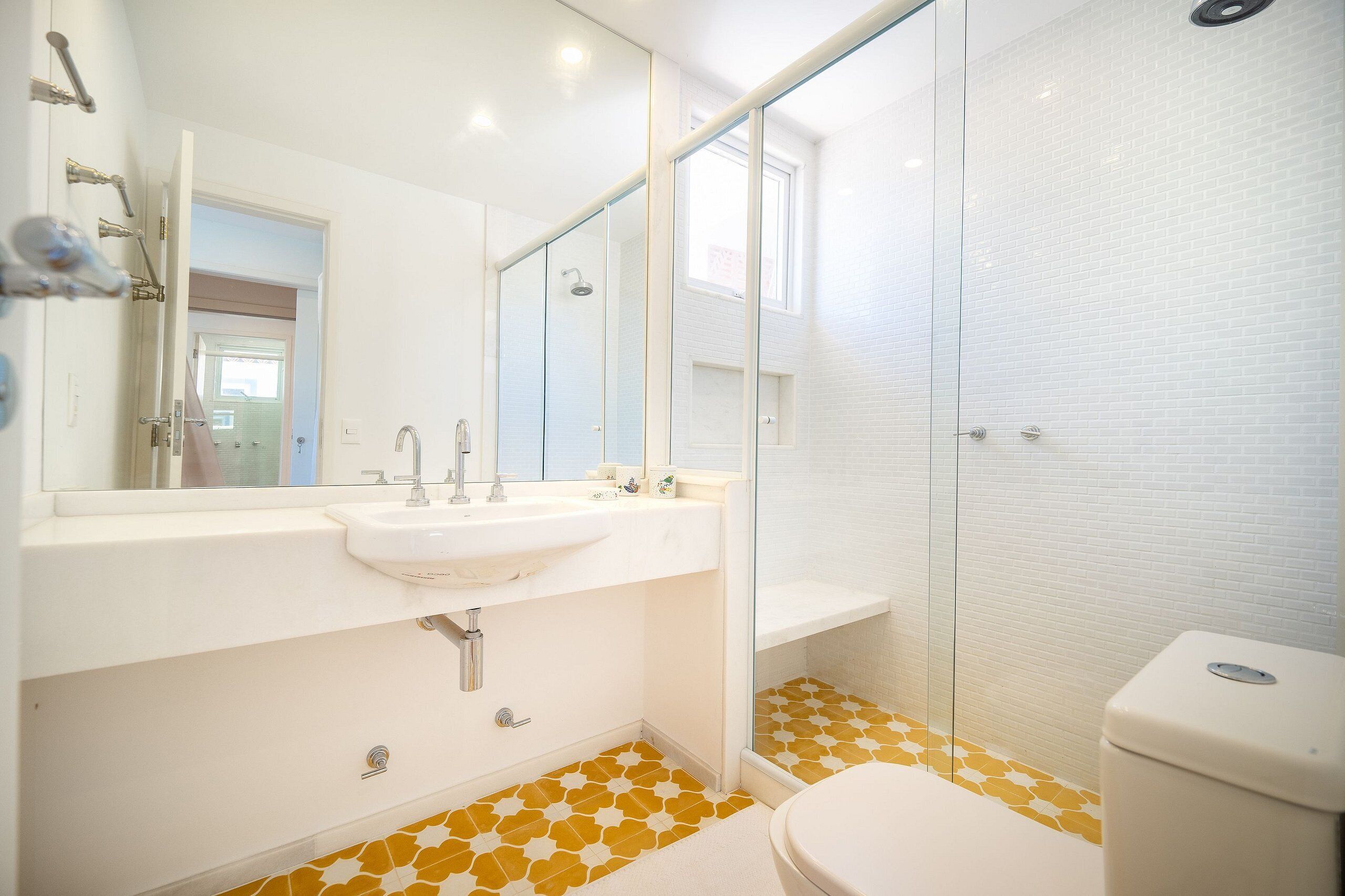 A modern bathroom with a white sink, mirror, and toilet, and a shower with glass doors.