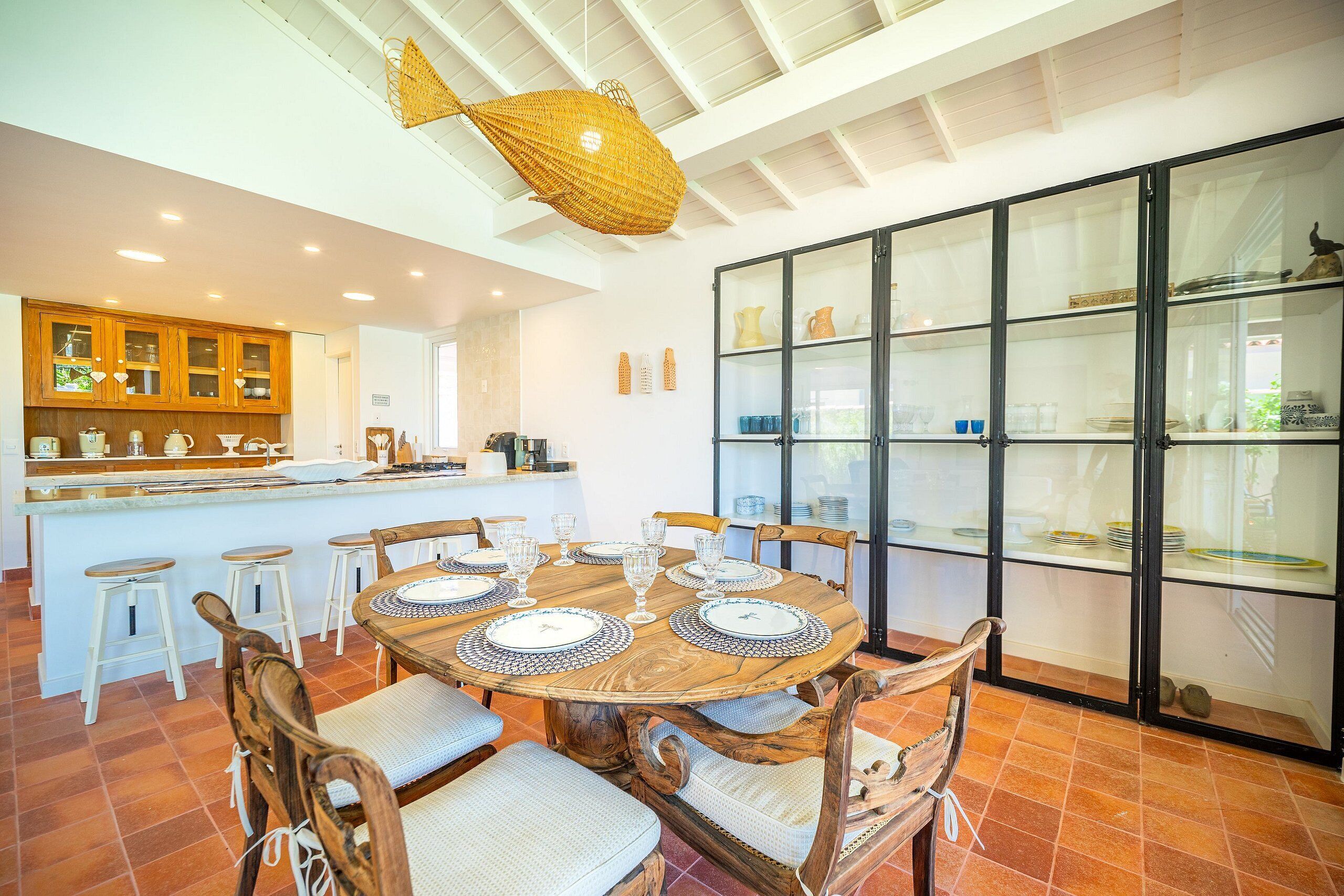Un comedor con una mesa redonda de madera, seis sillas y una isla central con taburetes.