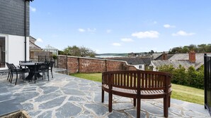 A patio with stone flooring, a wooden bench, and a table with chairs.