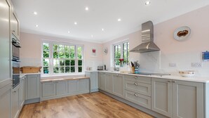 A kitchen with grey cabinets, a wooden countertop, and a window with a view of greenery.