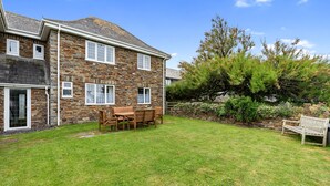 A stone house with a grassy yard, a wooden table, and a bench.