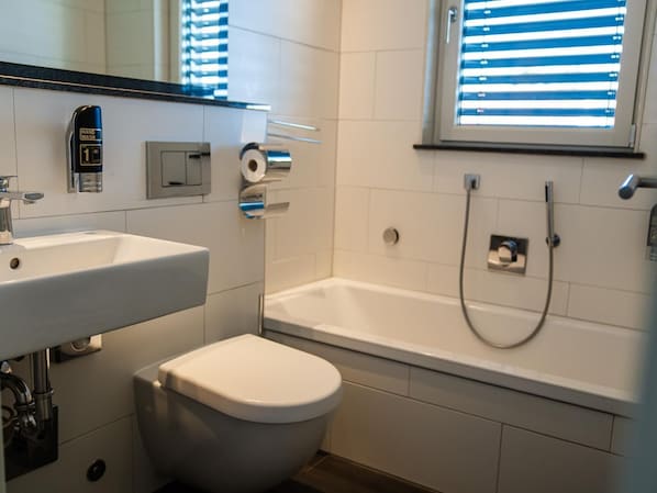 A modern bathroom with a toilet, sink, and bathtub. - KT Estates Resort Spa Frankfurt (Liederbach am Taunus)