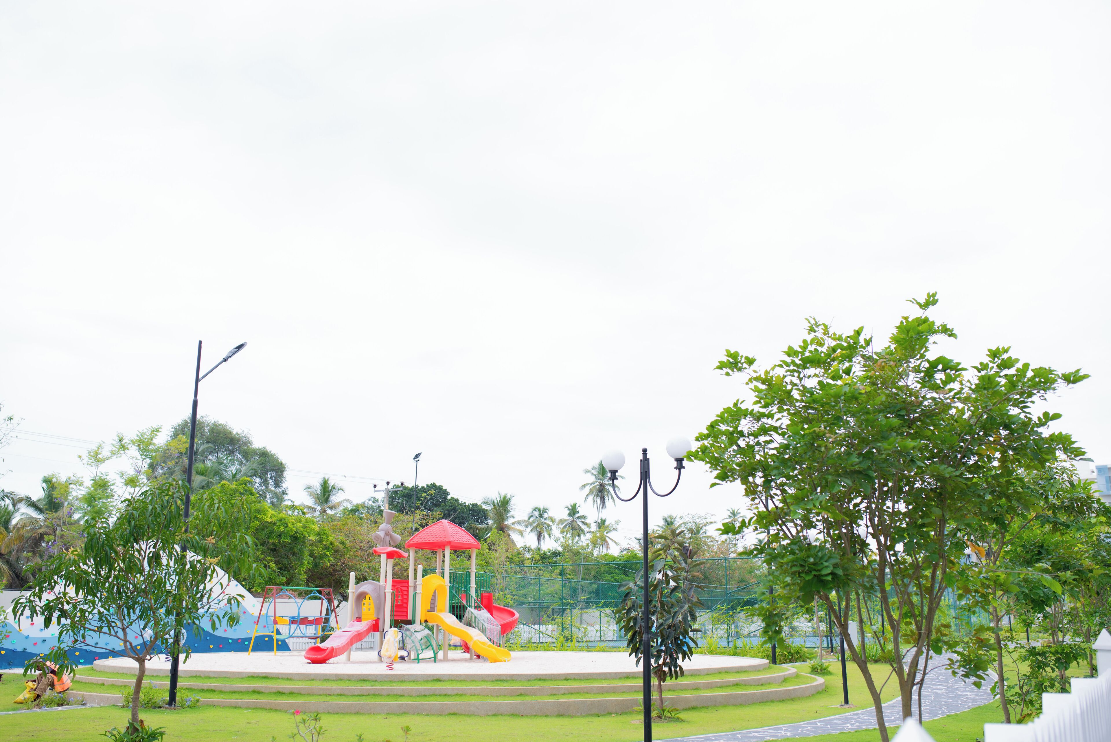 A playground with slides and climbing structures, surrounded by trees and a fence.