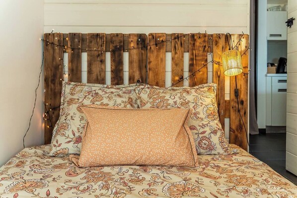 A bed with floral bedding, a wooden headboard, and a string of lights. - L'Ecrin Bohème (Saint-Paul)
