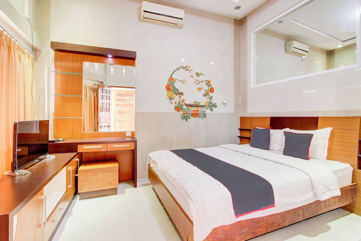 Quarto de hotel moderno com uma cama de madeira, uma escrivaninha e televisão de tela plana, e um guarda-roupa.