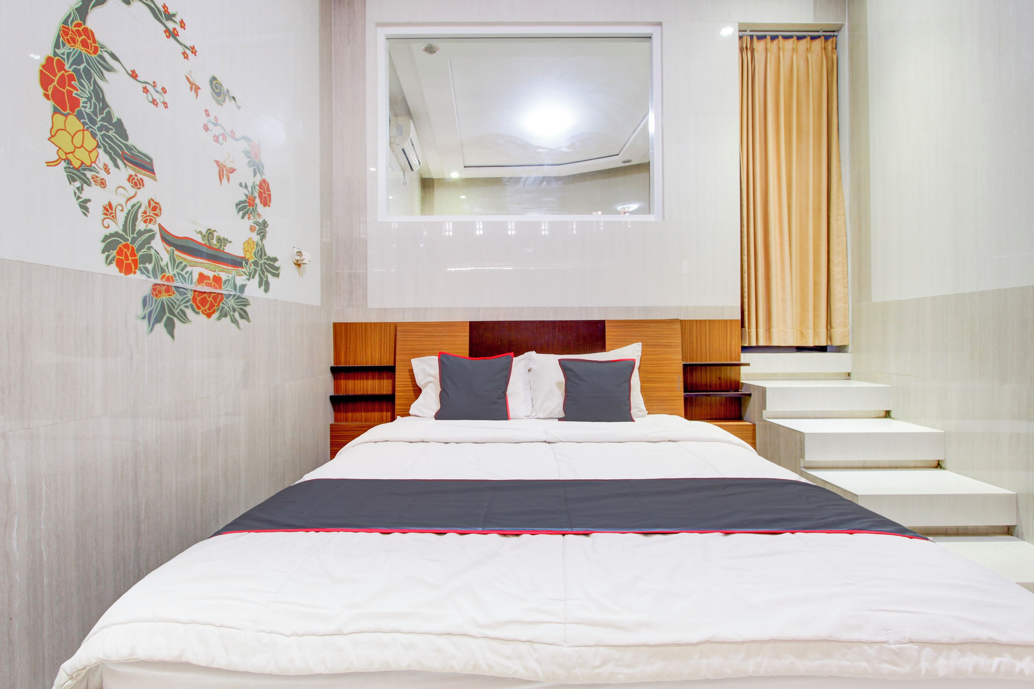 Una camera d'albergo moderna con un letto ben rifatto, una finestra con vista e una scala che conduce a un livello superiore.