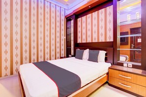 Une chambre d’hôtel avec un lit, une table de chevet en bois, un miroir et une armoire.