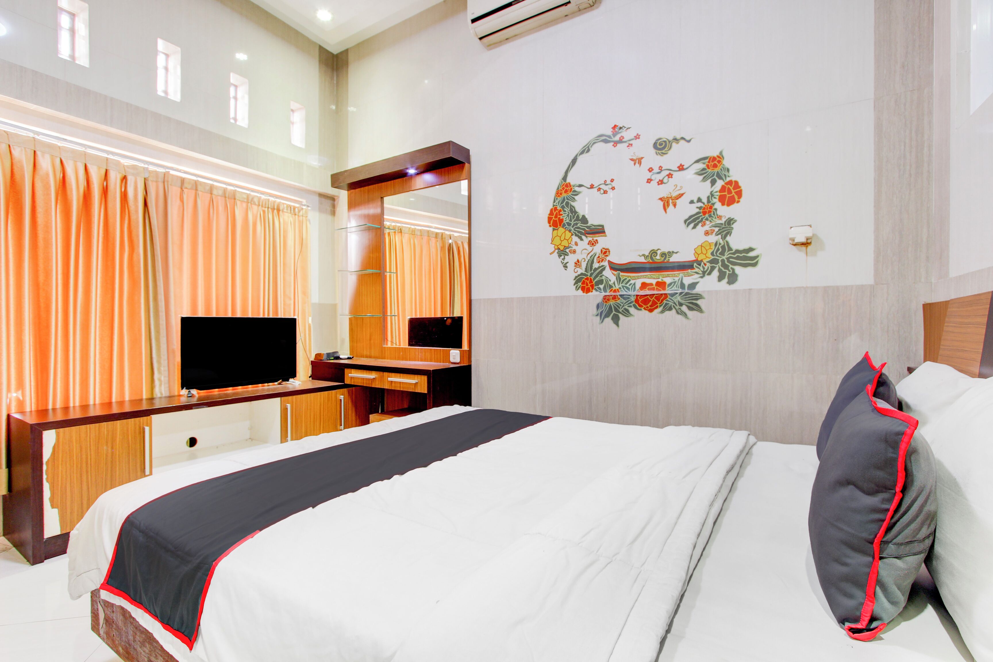 A hotel room with a bed, a desk, a television, and a mirror.