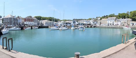 A harbor with boats docked, buildings along the shore, and a clear sky.