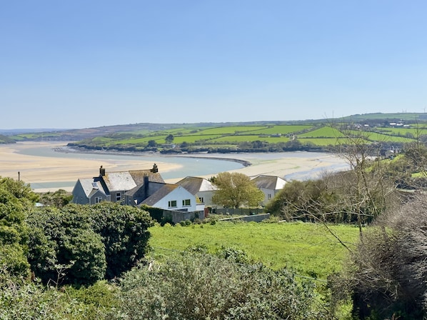 A coastal landscape with houses, green fields, and a river.