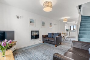 A modern living room with a sofa, TV, and artwork on the wall.