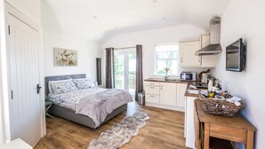 A bedroom with a bed, a small desk, a kitchen area, and a view of the outdoors. - The Stables at Ballygraffan, just outside Comber in the Strangford Lough area. (Comber)