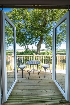 A wooden deck with two chairs and a table, overlooking a tree and a distant landscape. - The Stables at Ballygraffan, just outside Comber in the Strangford Lough area. (Comber)