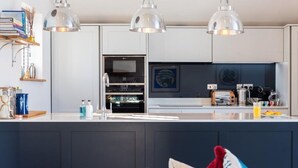 Una cocina moderna con armarios blancos, una isla central e iluminación colgante.