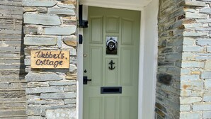 Eine Steinsäule mit einer grünen Tür und einem Schild, auf dem 'Webb's Cottage' steht.