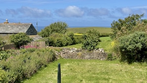 Eine ländliche Landschaft mit einer Steinmauer, einem Holzzaun und einem Haus mit geneigtem Dach.