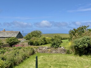A rural landscape with a stone wall, a wooden fence, and a house with a sloped roof.