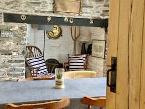 A rustic interior with stone walls, wooden furniture, and a metal bar above a fireplace.