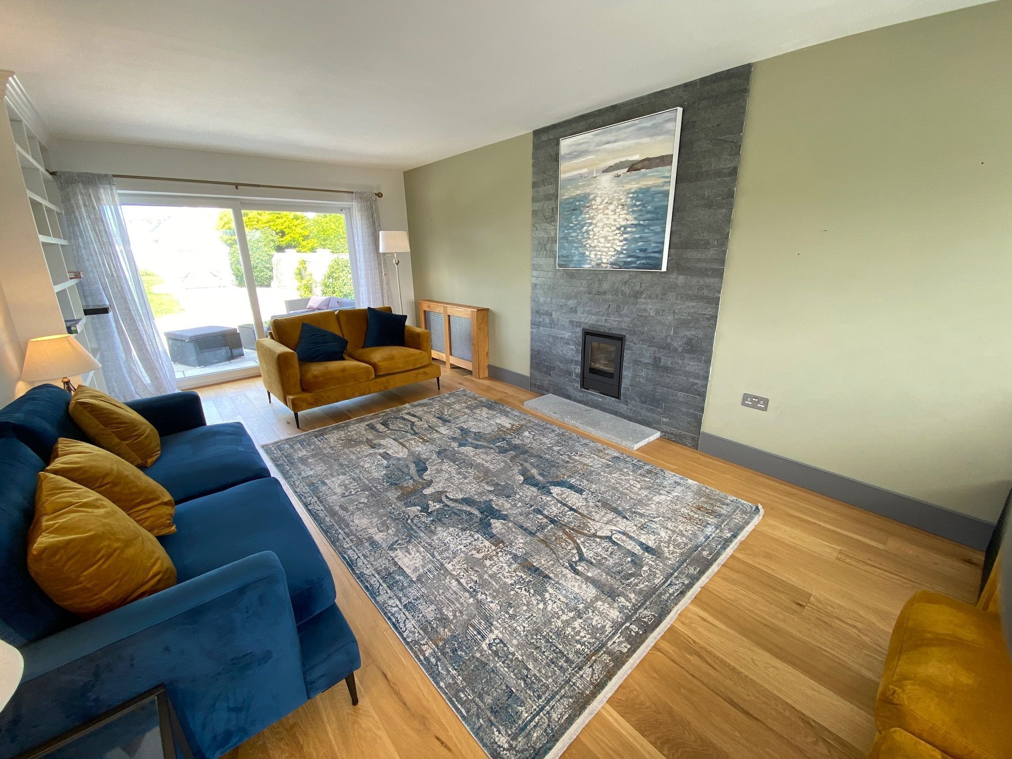 A living room with a sofa, a rug, a fireplace, and a painting on the wall.