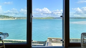 A room with a large sliding glass door leading to a seaside view. - 14 The Old Boatyard -with parking and  Incredible Estuary Views (Padstow)