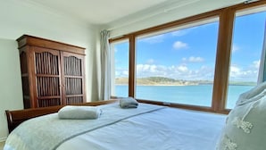Une chambre avec un grand lit, une armoire en bois et une vue sur la mer.