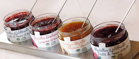 Four jars of fruit preserves on a metal tray.