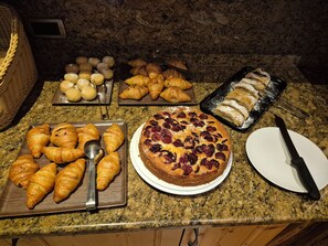 A variety of baked goods including croissants, a cherry pie, and pastries on a kitchen counter. - Hotel Hubertusstube (Laion)